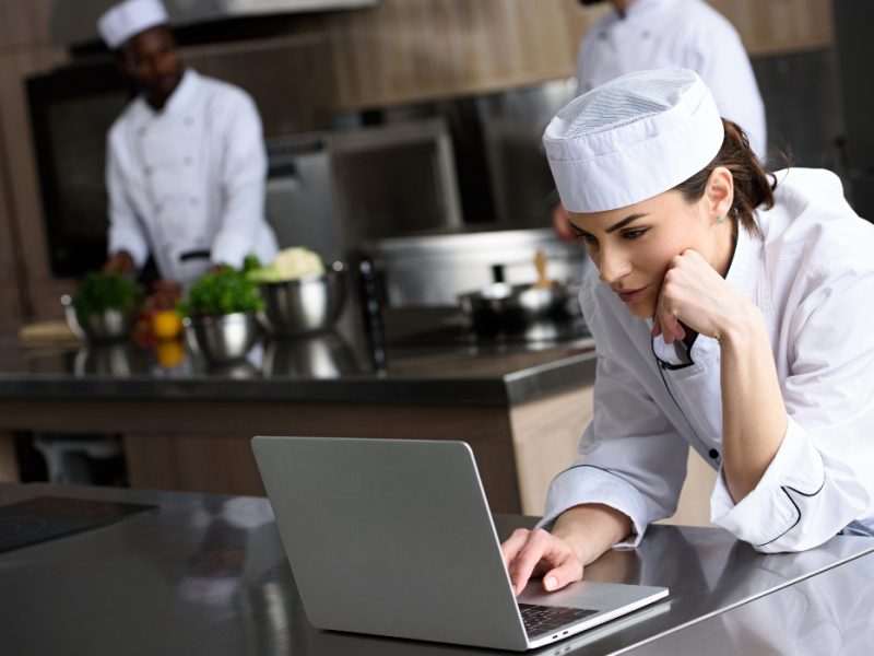 attractive chef using laptop at restaurant kitchen